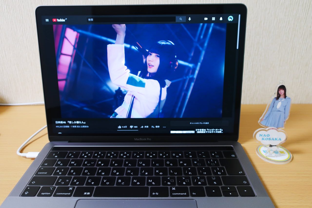 MacBook Proで「君しか勝たん」の動画を再生している横に、小坂菜緒のアクリルスタンドを置いた写真