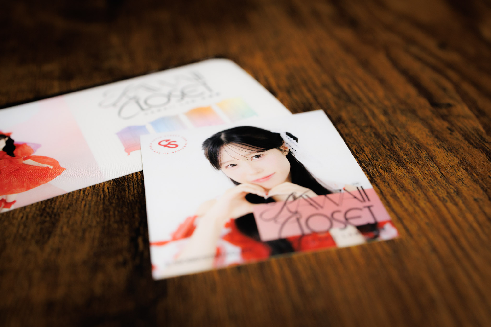 佐野愛花さんが両手でハートのポーズを作っている写真がプリントされているステッカーと、その後ろにチケットが写っています。