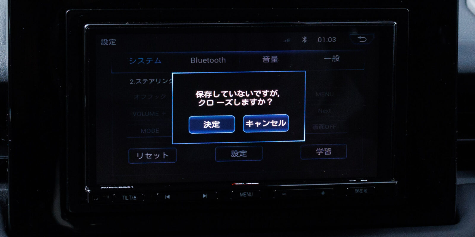 カーナビの設定画面に「保存していないですが, クロ ーズしますか？」という不自然な日本語のダイアログが表示されており、その下に「決定」「キャンセル」の2つのボタンがあります。